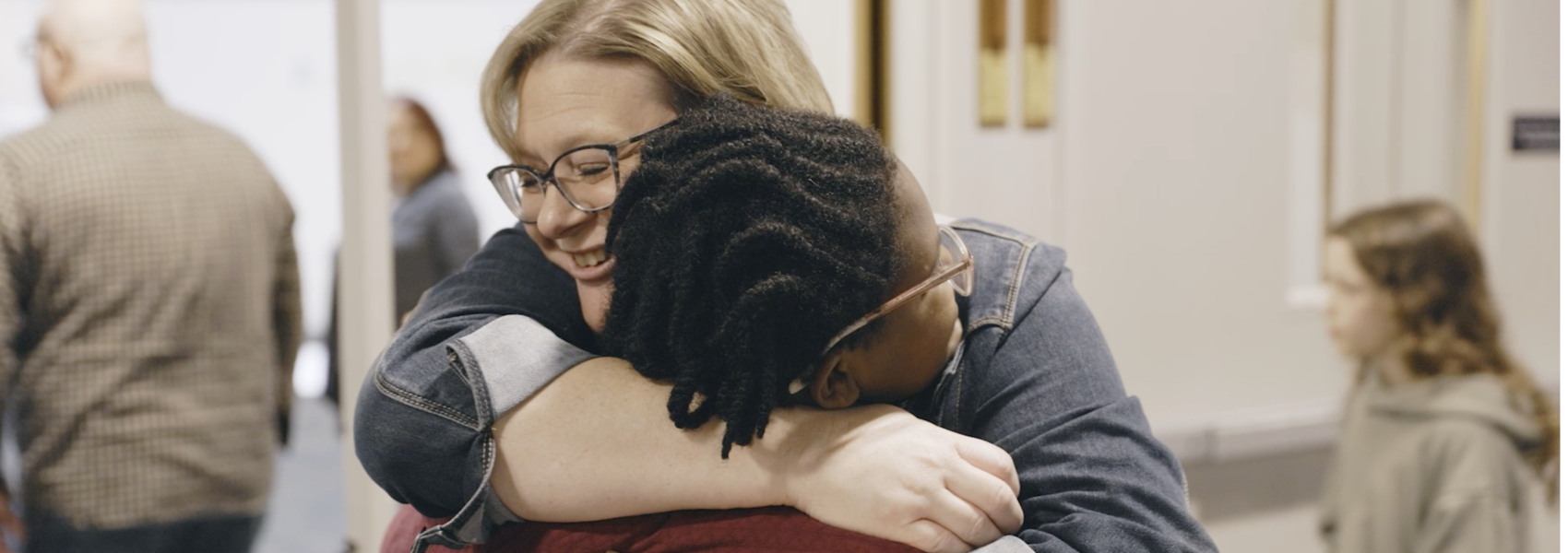 A church volunteer hugs a teen girl